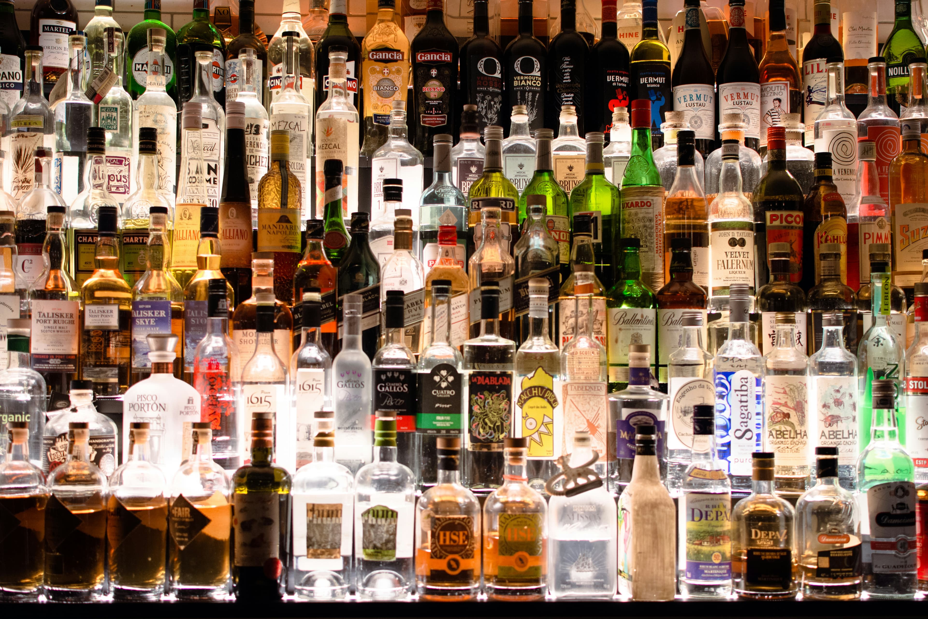 A backlit wall of whiskey, vodka, and liqueur bottles
